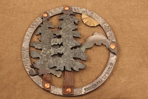 hand-hammered iron trivet with trees, mountain and sun