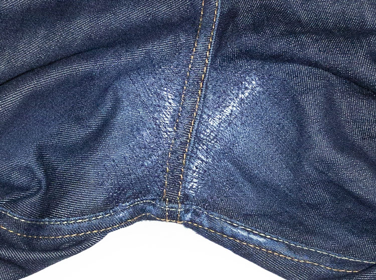 Finished close-up of repaired jeans with ripped crotch holes.