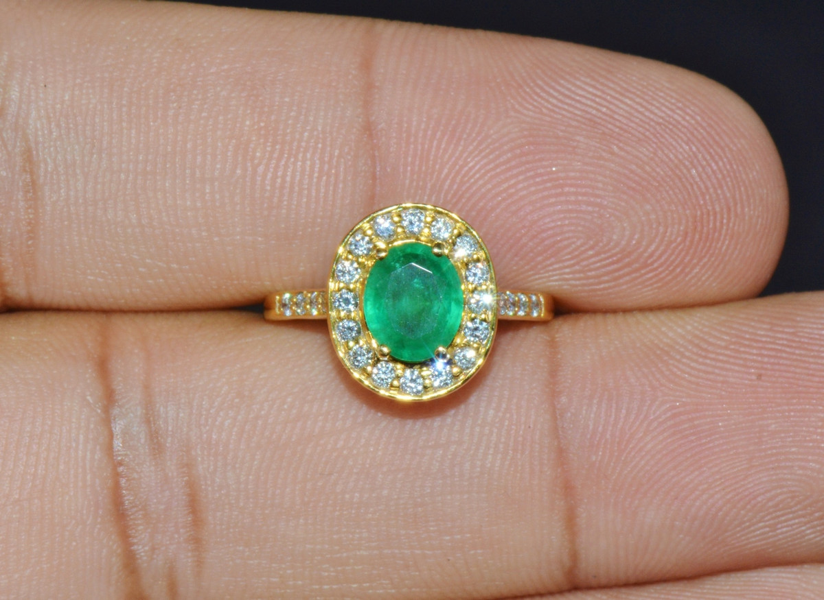Certified natural 18K solid gold 1.63CTS diamond and Zambian emerald ring. This ring is studded in center with a large oval cut natural Zambian emerald of 1.25CTS. The emerald is surrounded with 0.38CTS of natural round brilliant cut diamonds. The high quality natural diamonds and gems are set into solid heavy 18K yellow gold.