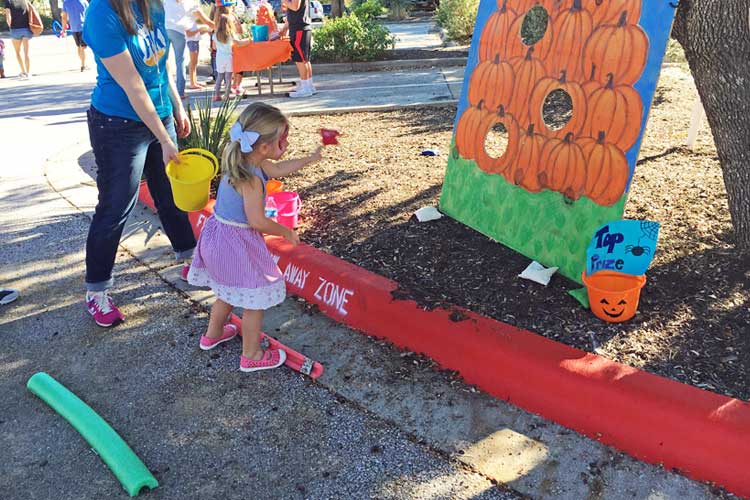 Cute toddler standing behind the lines at the pumpkin beanbag carnival game